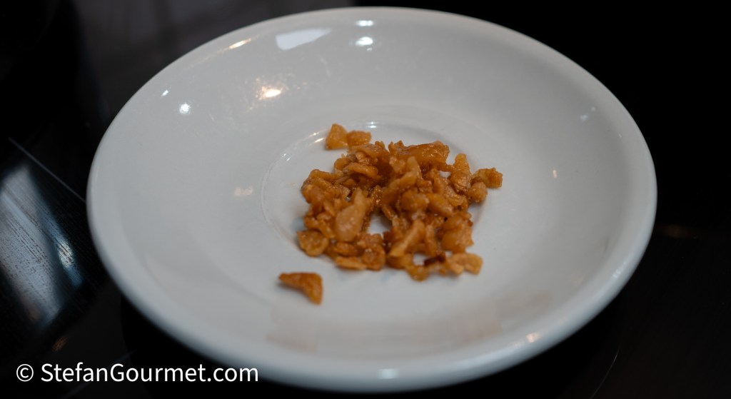 A small pile of crispy fried shallots on a white plate.