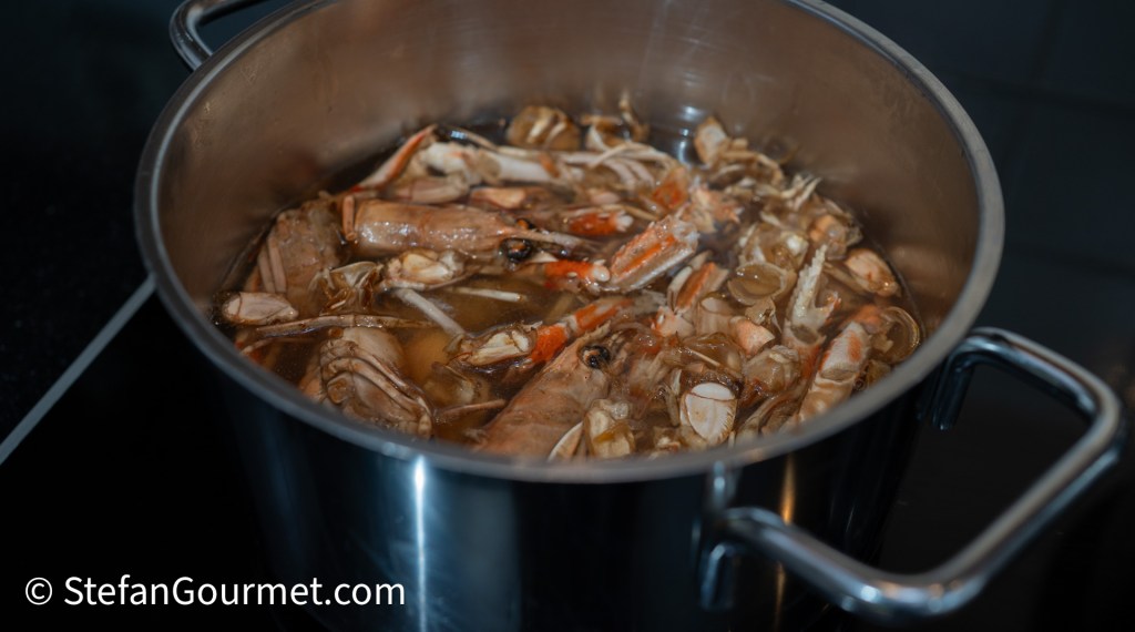 A pot filled with boiling seafood, including shrimp and shells, on a stovetop.