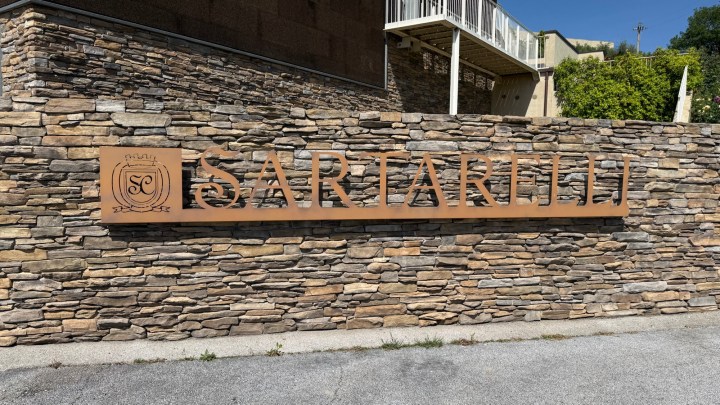 A stone wall with a prominent metal sign reading 'SARTARELLI'.