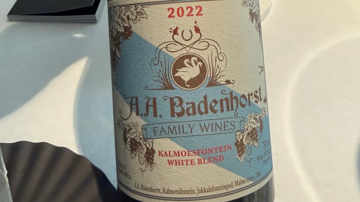 A close-up of a wine bottle label featuring 'A.A. Badenhorst Family Wines Kalmoesfontein White Blend 2022' with decorative elements and a swan illustration.